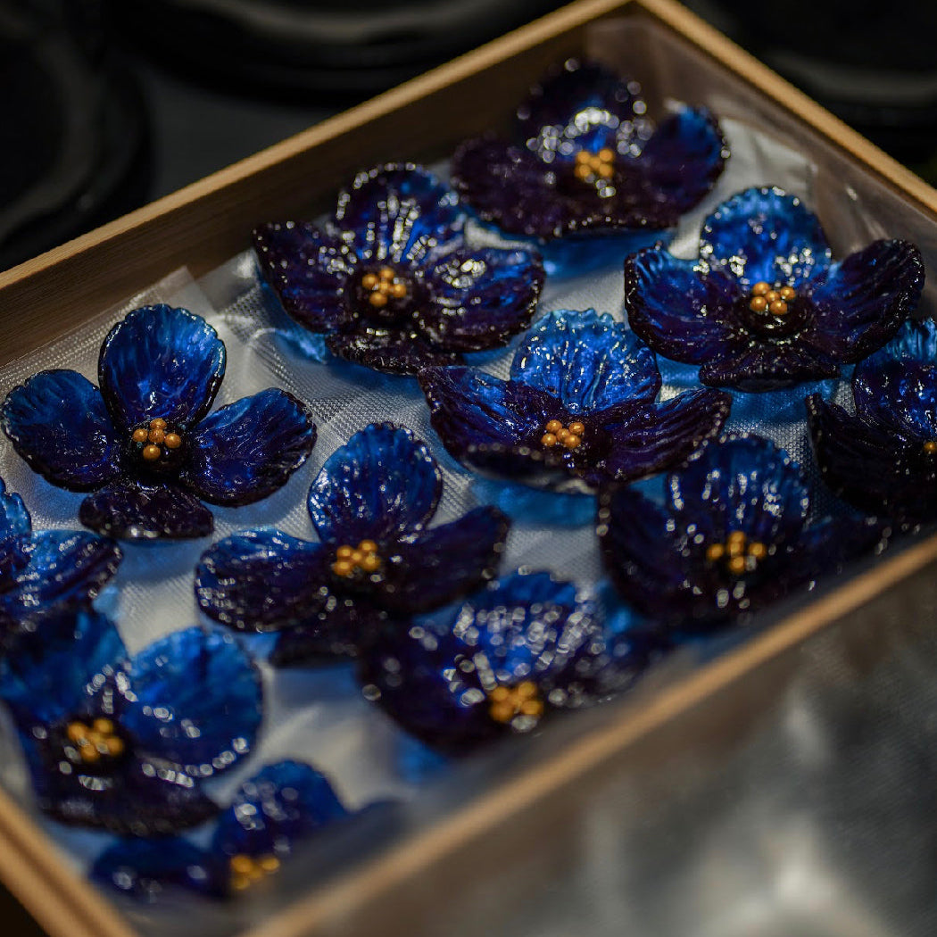 Box of blue flowers with gold centers on a dark background